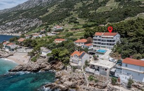A coastal residential area with houses, a swimming pool, and rocky terrain. - Nice apartment in Dingac with WiFi (Dingac)