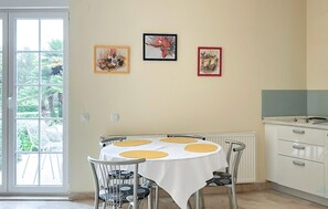 A dining area with a round table, chairs, and a white tablecloth. There are three framed artworks on the wall. - Gorgeous apartment in Trpanj with house sea view (Trpanj)