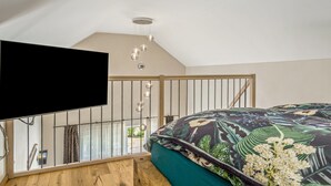 Ein Schlafzimmer mit einem großen Bett, einem Fernseher und einer Deckenleuchte.