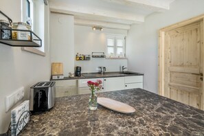 A kitchen with a marble countertop, a toaster, a coffee maker, and a vase with flowers.