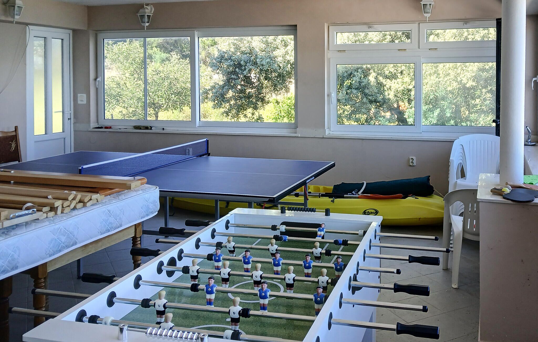 A room with a foosball table, a ping pong table, and a yellow inflatable raft.