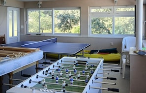 A room with a foosball table, a ping pong table, and a yellow inflatable raft. - Lovely apartment in Janjina with house sea view (Janjina)