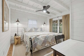 A bedroom with a bed, bedside lamps, a ceiling fan, a window with curtains, and a table. - Peace of Aska w/ Hot Tub (Blue Ridge)
