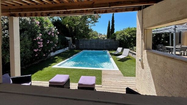 A swimming pool with a wooden deck and lounge chairs, surrounded by greenery and a pergola. - A large, charming vacation rental, formerly a wine cellar, located along the Canal du Midi. (marseillette)