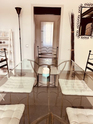 A dining area with a glass table and chairs, a lamp, and a decorative mirror. - A large, charming vacation rental, formerly a wine cellar, located along the Canal du Midi. (marseillette)
