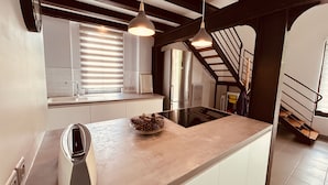 A modern kitchen with a built-in stove, a sink, and a large island. There is a staircase leading to an upper level. - A large, charming vacation rental, formerly a wine cellar, located along the Canal du Midi. (marseillette)