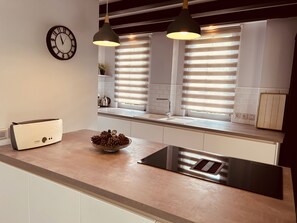 Eine moderne Küche mit einem Bosch-Toaster, einer Schale Kiefernzapfen und einem Fenster mit Jalousien.