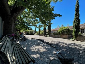 A gravel driveway leading to a wooden fence, a bench, and a bicycle with flowers. - A large, charming vacation rental, formerly a wine cellar, located along the Canal du Midi. (marseillette)