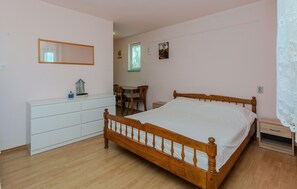 Un dormitorio con una cama de madera, un tocador blanco, un escritorio y una silla.