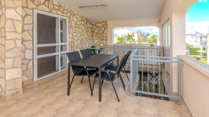 An outdoor balcony with a stone wall, a table with chairs, and a view of the neighborhood. - Stunning apartment in Zukve (Zukve)