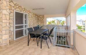 Ein Balkon im Freien mit Steinmauer, Tisch mit Stühlen und Blick auf die Nachbarschaft.