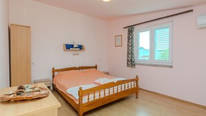 A bedroom with a wooden bed, a bedside table with a decorative item, a window with blinds, and a door. - Stunning apartment in Zukve (Zukve)