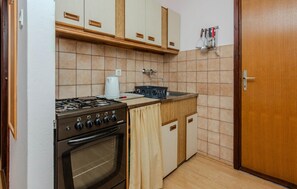 Eine kleine Küche mit Gasherd, Backofen und Kaffeemaschine.