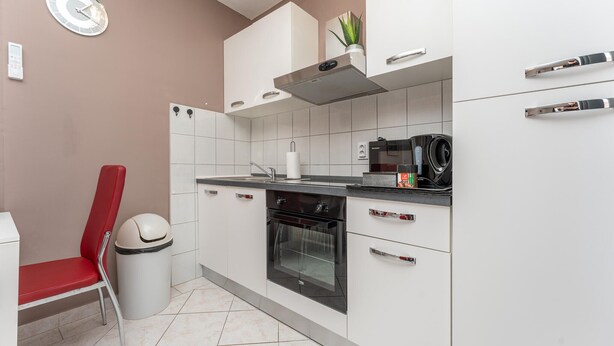 A modern kitchen with white cabinets, a black countertop, a microwave, and a stainless steel range hood. - Awesome apartment in Biograd na Moru with WiFi (Biograd na Moru)
