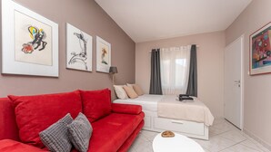 A compact bedroom with a red sofa, a bed with a white duvet, a small round table, and artwork on the walls. - Awesome apartment in Biograd na Moru with WiFi (Biograd na Moru)