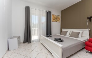 A bedroom with a bed, a red chair, a painting, and a window with curtains. - Beautiful apartment in Biograd na Moru with WiFi (Biograd na Moru)