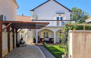 A two-story house with a covered patio area, a small garden, and a seating arrangement. - Beautiful apartment in Biograd na Moru with WiFi (Biograd na Moru)