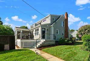 A two-story house with a front porch, a chimney, and a well-maintained lawn. - Classic 3 Bedroom Eastport Cottage with Large Yard and Free Parking (Annapolis)
