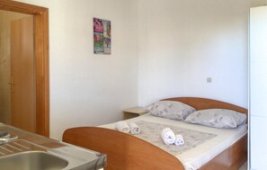 Ein Schlafzimmer mit einem Bett, einem Nachttisch, einem Badezimmer mit einem Waschbecken und einer Tür.