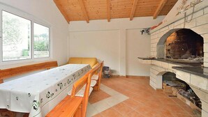 Ein Zimmer mit Holzboden, Kamin, Tisch mit Blumendecke und einer Bank.
