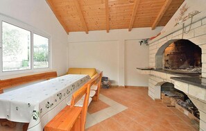 Ein Zimmer mit Holzboden, Kamin, Tisch mit Blumendecke und einer Bank.