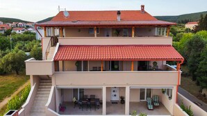 A two-story building with a red-tiled roof, balconies, and a covered outdoor seating area. - Gorgeous apartment in Sveti Petar na Moru (Sveti Petar na Moru)