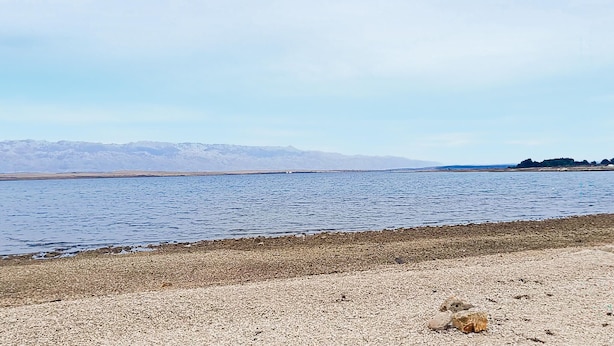 A pebbly beach with a calm lake and distant mountains. - Amazing apartment in Vir with WiFi (Vir)