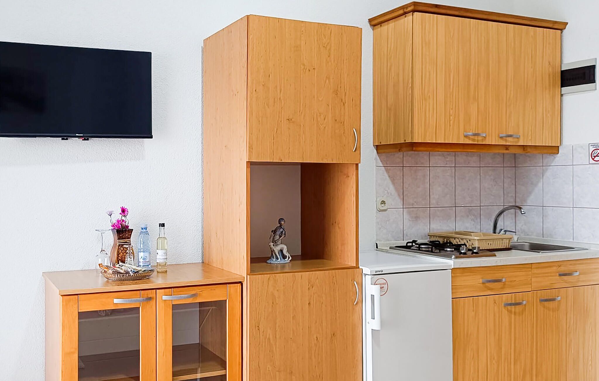 A compact kitchen with wooden cabinets, a built-in stove, and a sink.