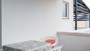 A balcony with a white chair and a table, a window, and a metal railing. - Amazing apartment in Vir with WiFi (Vir)