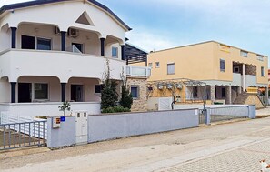 Ein zweistöckiges Wohngebäude mit flachem Dach, einem Balkon und einem verschlossenen Eingang.