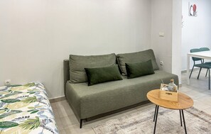Ein Wohnzimmer mit einer Couch, einem kleinen runden Tisch und einem Teppich mit Muster.