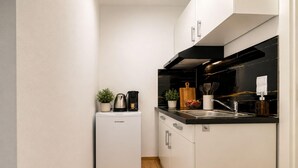 A compact kitchen with a built-in dishwasher, a coffee maker, and a small potted plant. - Zum Rheinberg – Komfort Studio (Braubach)