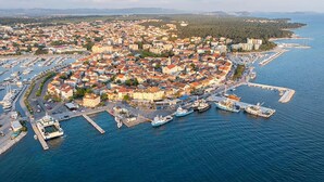Une vue aérienne d’une ville côtière avec un port de plaisance, des habitations densément regroupées et une vue dégagée sur la mer.