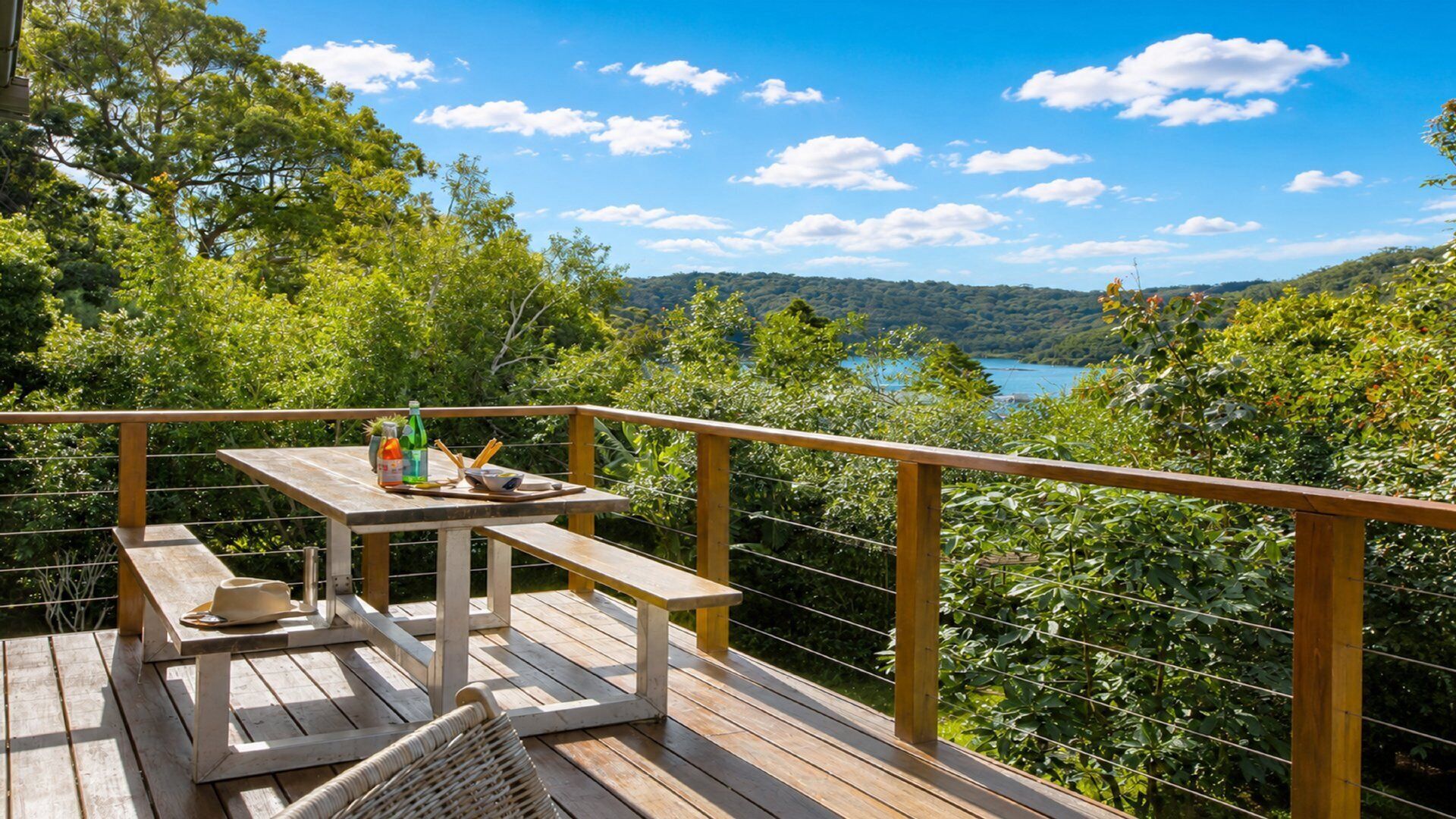 A wooden deck with a table and benches overlooking a lake surrounded by trees.