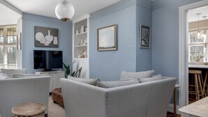 A living room with a sectional sofa, a television, and a decorative pendant light. - East Lodge (Peterborough)