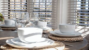 A table set with white plates, bowls, and glasses, with woven placemats and a woven basket. - East Lodge (Peterborough)