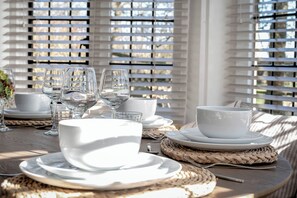 A table set with white plates, bowls, and glasses, with woven placemats and a woven basket. - East Lodge (Peterborough)