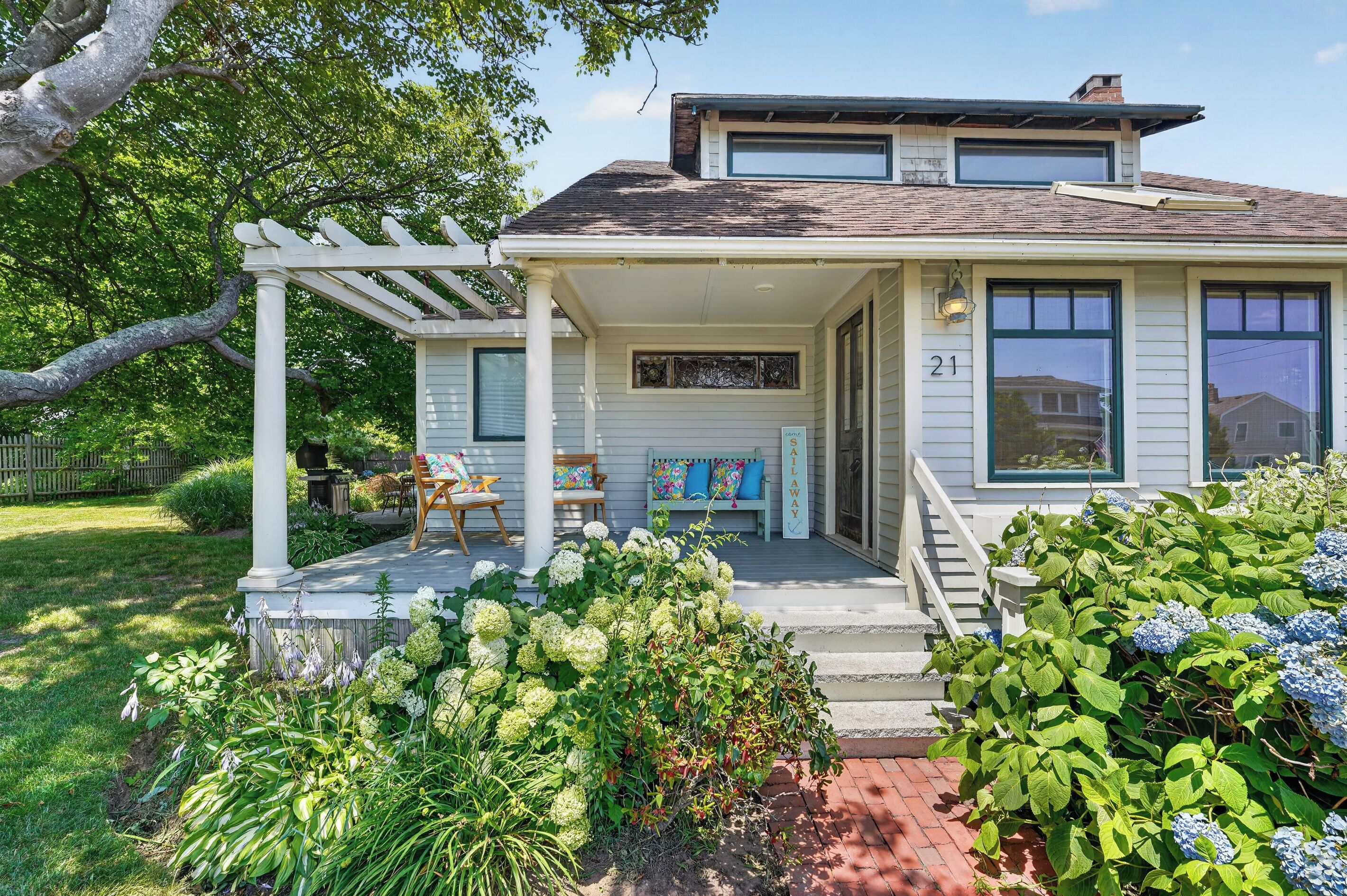 A two-story house with a covered porch, a garage, and a well-maintained garden with hydrangeas.
