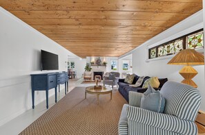 Un soggiorno moderno con soffitto in legno, televisore, divano e camino.