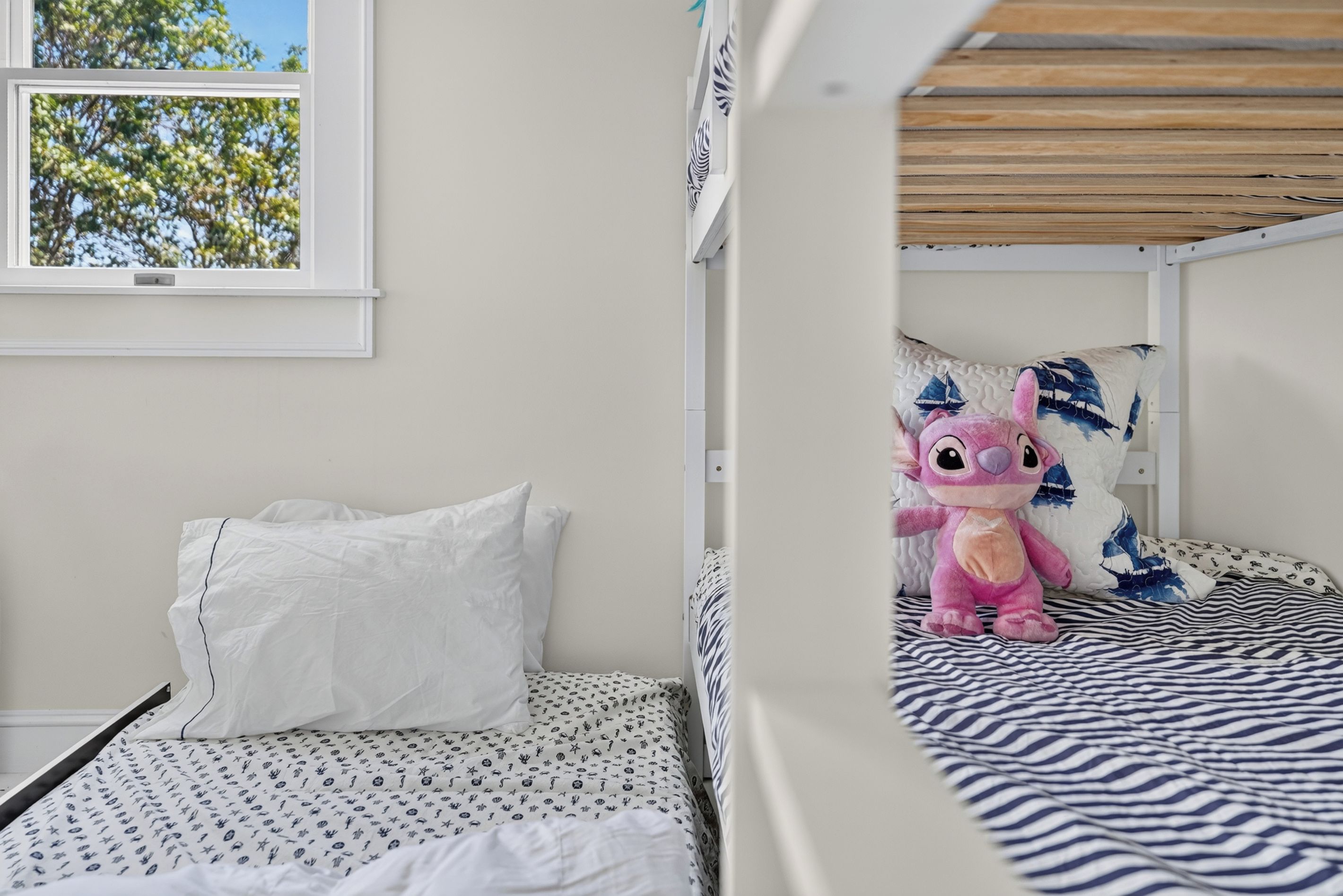 A bunk bed with a window, a white pillow, and a stuffed toy on the bed.