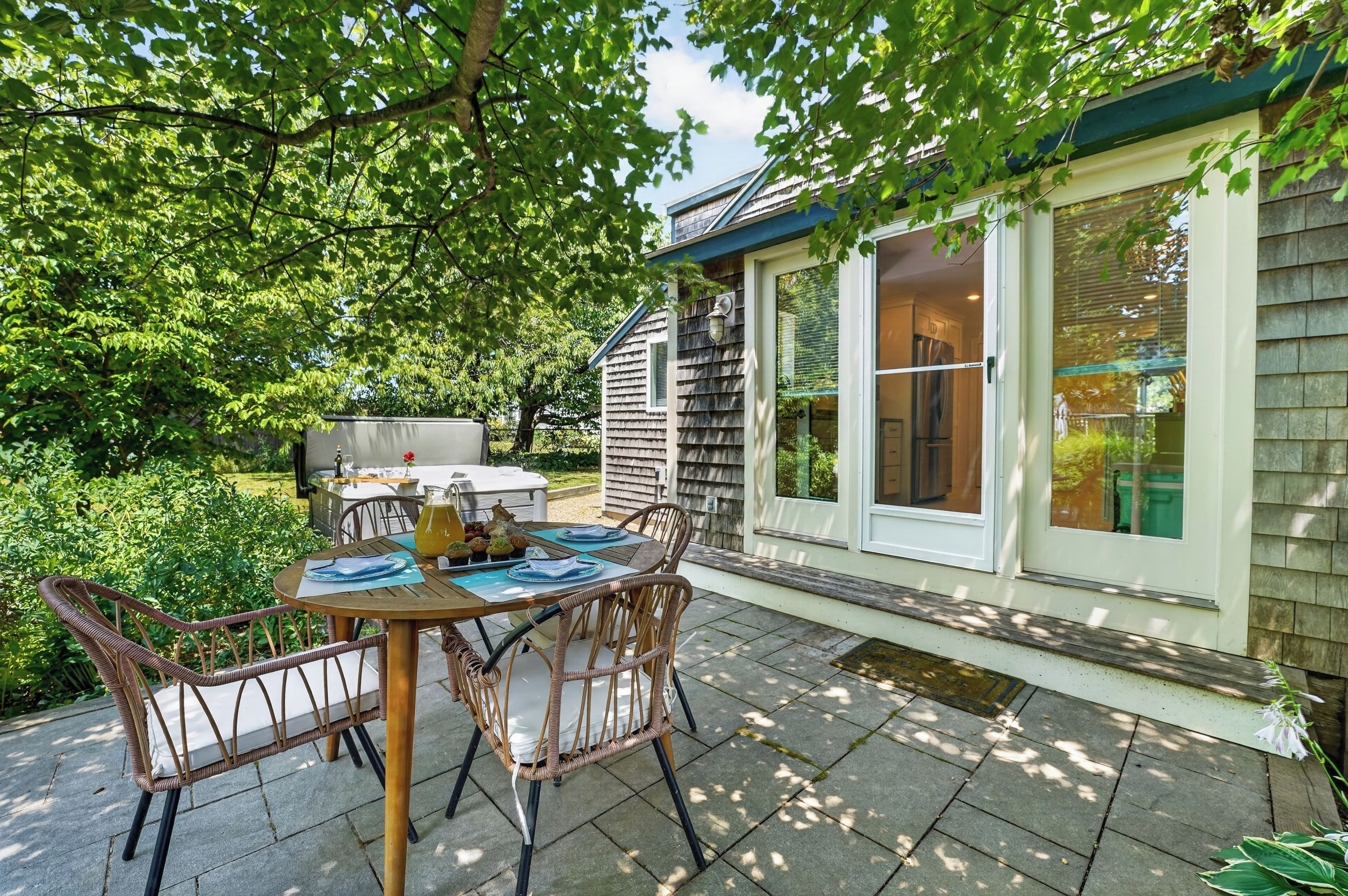 Un patio con tavolo e sedie, un barbecue e una casa con una finestra che si affaccia sul giardino.