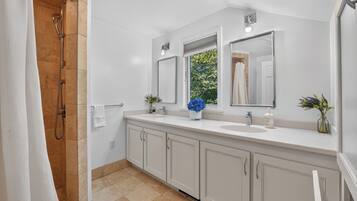 Un baño moderno con ducha, lavamanos y espejo.