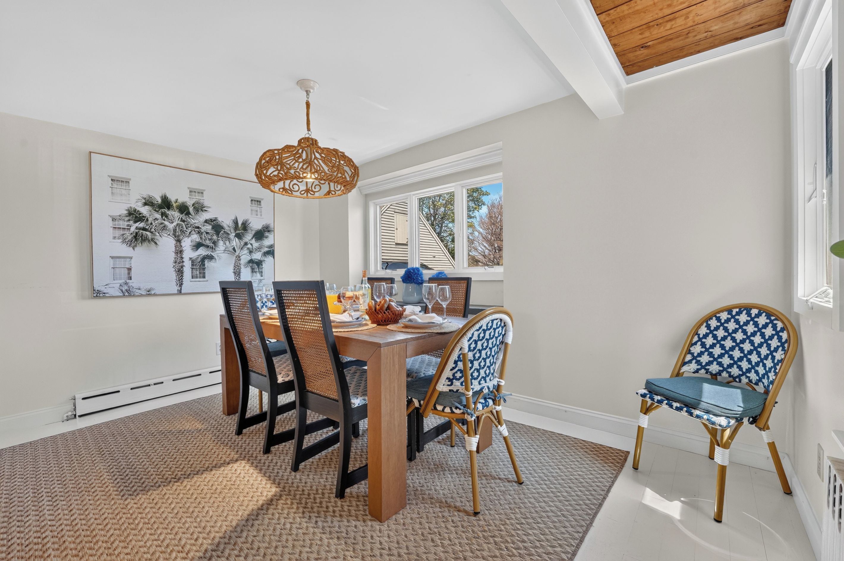 A dining area with a wooden table, chairs, and a hanging light fixture.