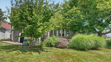 A residential property with a well-maintained lawn, a variety of shrubs, and a tree providing shade.