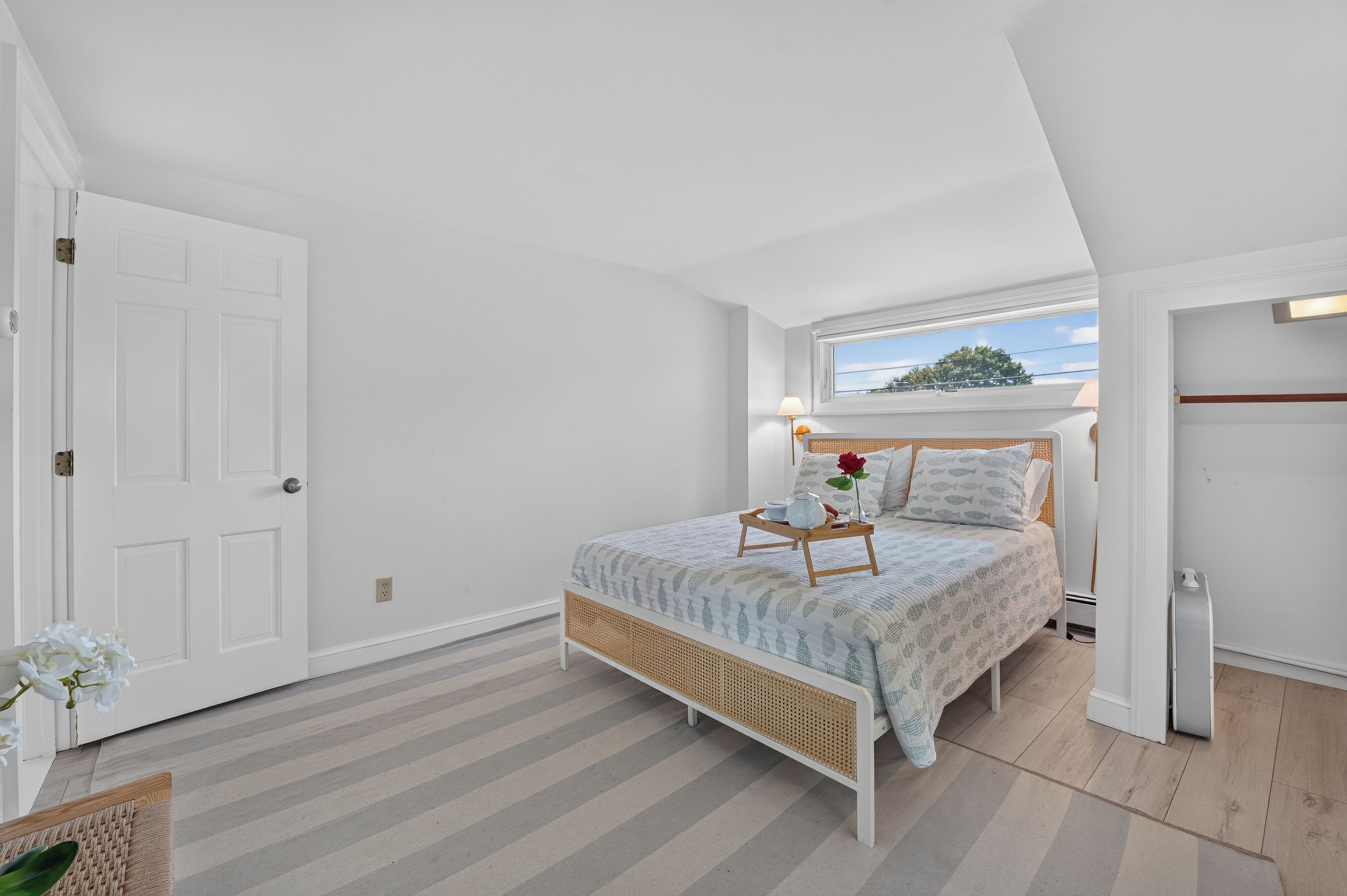 Quarto com cama, mesa de cabeceira e janela com vista.