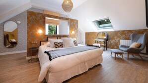 Una camera da letto con un letto grande, un comodino, una sedia, una lampada a sospensione e una finestra.