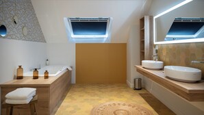 Un bagno moderno con una vasca, due lavabi, un mobile lavabo e una finestra.