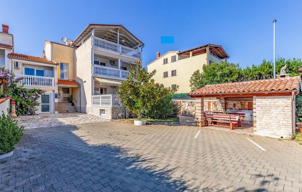 A courtyard with a paved area, a small outdoor seating area, and buildings with balconies and a stone wall. - Gorgeous apartment in Banjole with WiFi (Banjole)