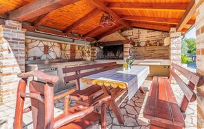 An outdoor kitchen with a stone wall, wooden ceiling, and a bench. - Gorgeous apartment in Banjole with WiFi (Banjole)