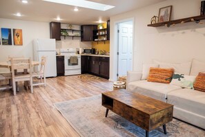 A modern living room with a sofa, coffee table, and a dining area with chairs. - Sunnsyide Casita - A/C, bikes provided, central location near downtown & trails (Flagstaff)